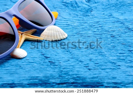 sunglasses and shells on wooden blue background with place for text