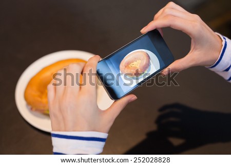Young woman taking a photo of her lunch at the cafe