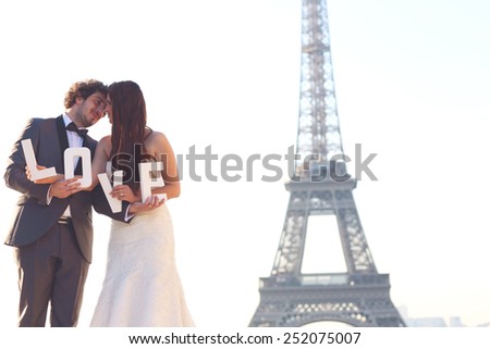 Bride and groom holding LOVE letters in their hand in Paris, France 