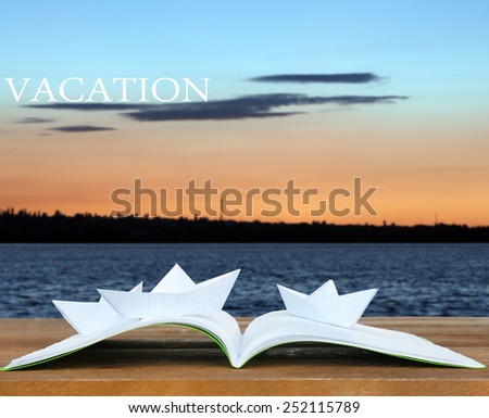 Origami boats on book on nature background