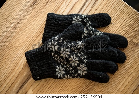 Closeup photo of black knitted gloves lying on wooden table