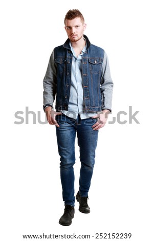 full length picture of a casual serious young man walking towards the camera  isolated over a white background