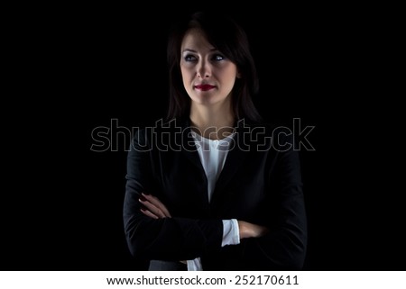 Portrait of serious looking away brunette business woman on black background