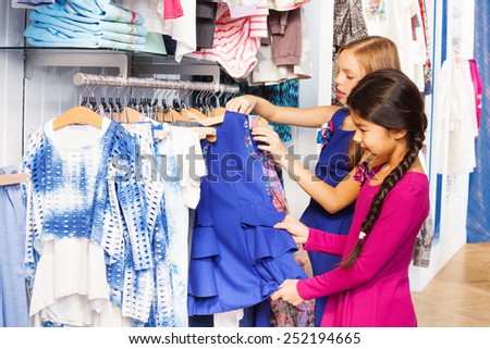 Two small girls shop together in the clothes store