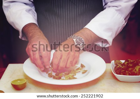 Chef is mixing salad at professional kitchen, toned picture