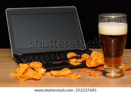 open laptop with chips scattered on keyboard isolated on black background - stock photo