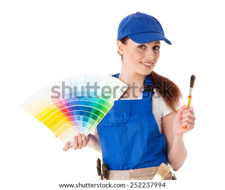 Young woman in  coverall with a color guide and paintbrushes on a white background.