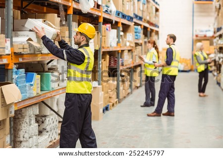Warehouse worker taking package in the shelf in a large warehouse in a large warehouse Royalty-Free Stock Photo #252245797