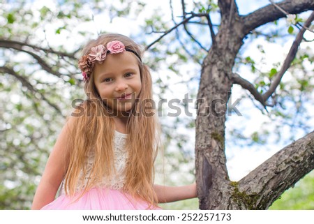 Happy little adorable girl in blossoming apple tree garden