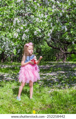Adorable little girl have fun in blossoming apple tree garden at may
