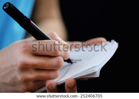 Sportsman signing autograph on small notebook on black background