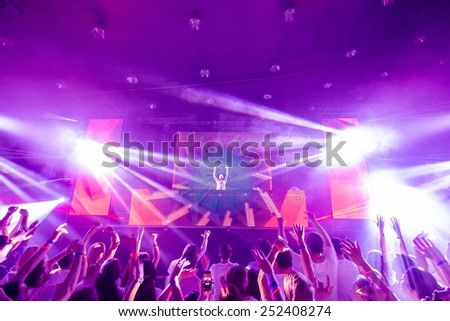 Picture of dj concert, music festival, party in nightclub, dance floor, disco club, many people standing with raised hands up and clapping, happiness and night life concept.