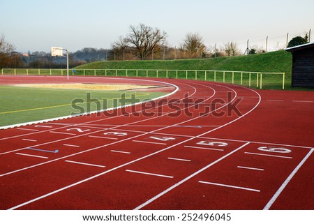 Stock image of a football field with running track and clubhouse in the evening, signifying concept of dreams and aspirations Royalty-Free Stock Photo #252496045