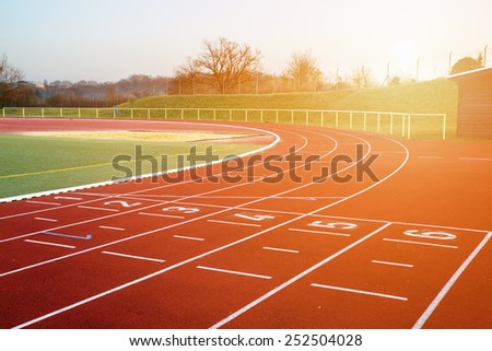 Stock image of a running track in an evening sunset signifying concept of dreams and aspirations Royalty-Free Stock Photo #252504028