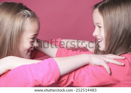 young sister girl poses for a picture isolated on pink