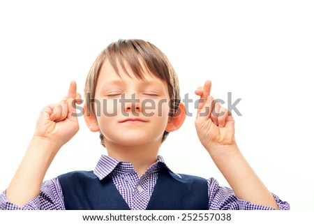 Waiting for a special moment. Closeup of adorable little boy in formalwear keeping his fingers crossed and eyes closed while standing isolated on white background with copy space