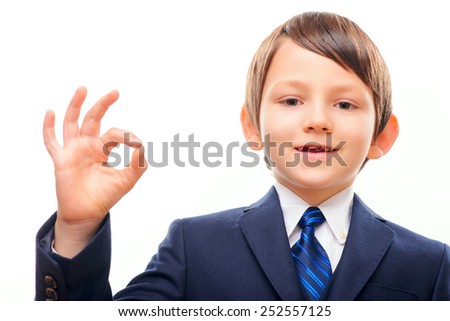 It is perfect. Closeup portrait of a business child wearing suit and tie showing OK sign while standing isolated on white background