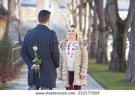 Romantic young man awaiting his girlfriend with a rose behind his back