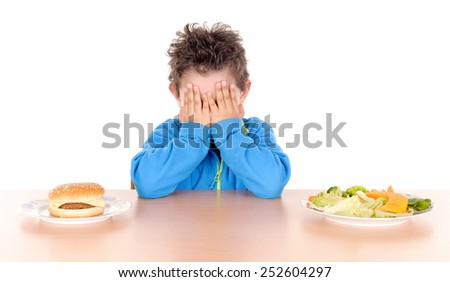 little boy torn between hamburguer and vegetables isolated in white background