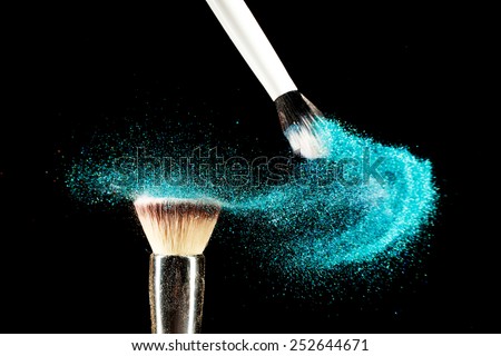 Art of visage.  Horizontal closeup photo of two professional black make-up brushes with blue powder isolated on black background with copy place