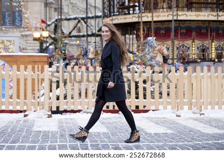 Portrait in full growth of a beautiful young brown haired woman on the background of a winter amusement park