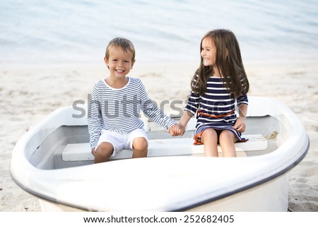Happy children sitting in the boat in the beach