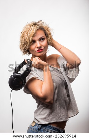 Girl in headphones. Blonde listening to music on stereo headphones. Emotions while listening to music.
