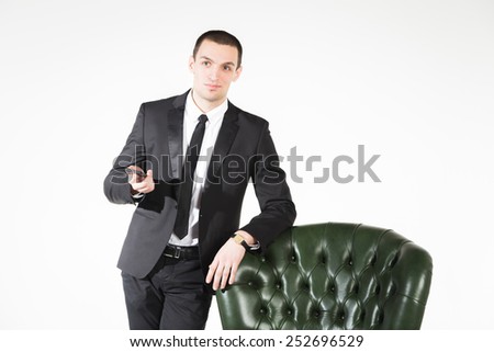 Business man sitting on a green leather chair on a light background. Success, business, young and successful.