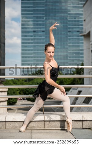 Ballet dancer (ballerina) dancing on street with business buildings in background