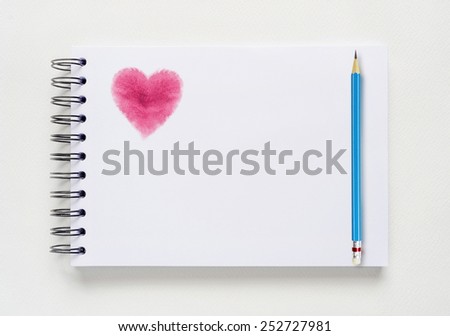 White notebook background with heart shape of watercolor painted brushes and blue pencil.