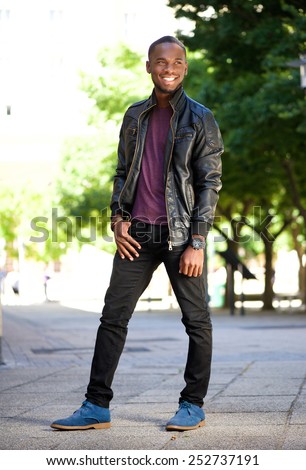 Full length portrait of a smiling young african american man in black leather jacket