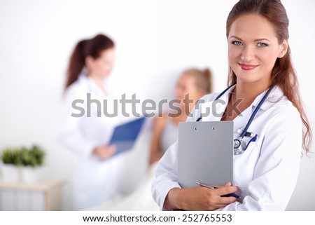 Smiling female doctor with a folder in uniform standing 