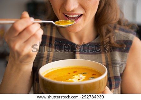 Closeup on young woman eating pumpkin soup in kitchen Royalty-Free Stock Photo #252784930