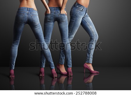 three perfect shaped woman in a dark room, wearing jeans Royalty-Free Stock Photo #252788008