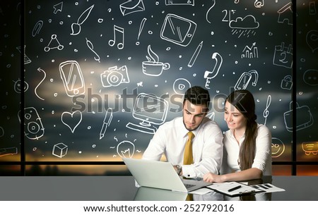 Business couple sitting at table with hand drawn social media icons and symbols 