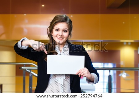 Smiling young beautiful girl shows on blank white card