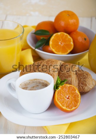 Fresh Morning coffee with croissants, tangerines and juice on a wooden table