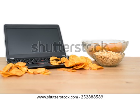 open laptop with chips scattered on keyboard isolated on white background - stock photo