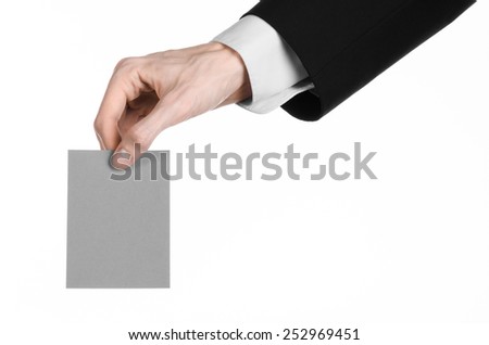 Business and advertising topic: Man in black suit holding a gray blank card in hand isolated on white background in studio