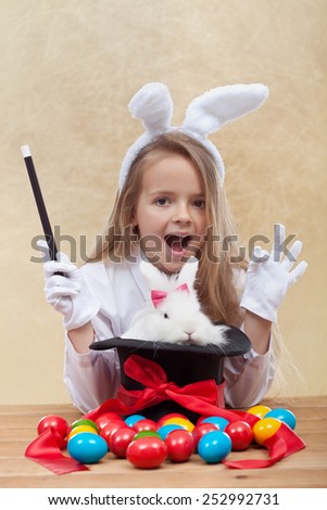 Little magician girl conjuring the easter bunny and colorful eggs- shallow depth of field