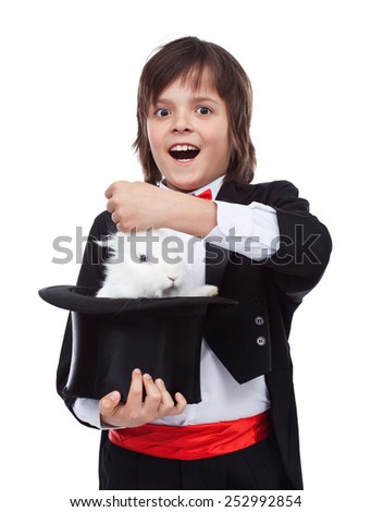 Young magician boy taking a cute white rabbit out of the hat - excited by his success