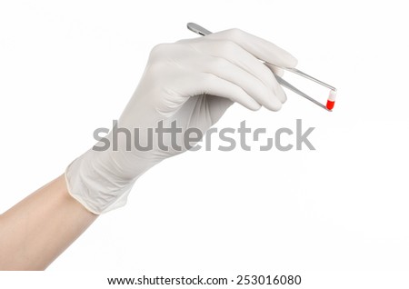 Pharmacology and Medical theme: doctor's hand in a white glove holding tweezers with red pill capsule isolated on white background in studio