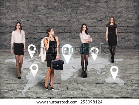 Four women standing in front of an earth map on grey brick background