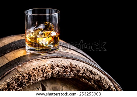 Glass of whisky with ice on old wooden barrel Royalty-Free Stock Photo #253255903
