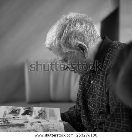 Side shot of a senior man reading a book, indoor shot with shallow depth of field