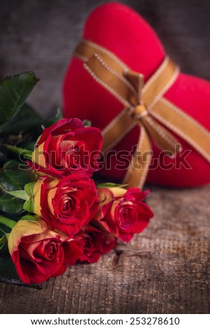 Beautiful flowers roses and decorative heart on vintage dark  wooden background.  Selective focus. 