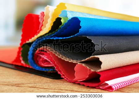Colorful fabric samples on wooden table and light blurred background Royalty-Free Stock Photo #253303036