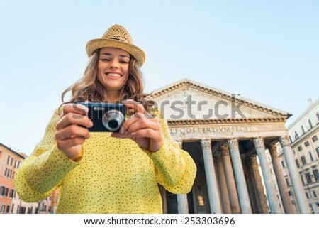 Portrait of happy young woman checking photos in camera in front of pantheon in rome, italy