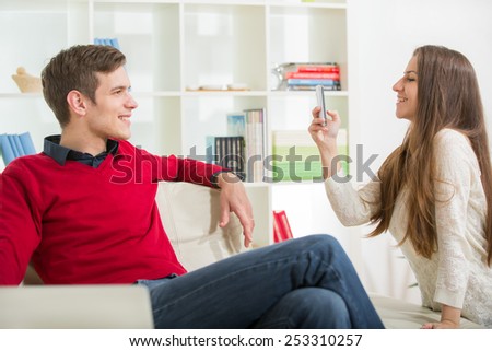 Girl photographs her boyfriend in the living room.Selective focus