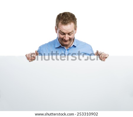 Young man making funny face, holding a blank sign board. Studio shot on white background.